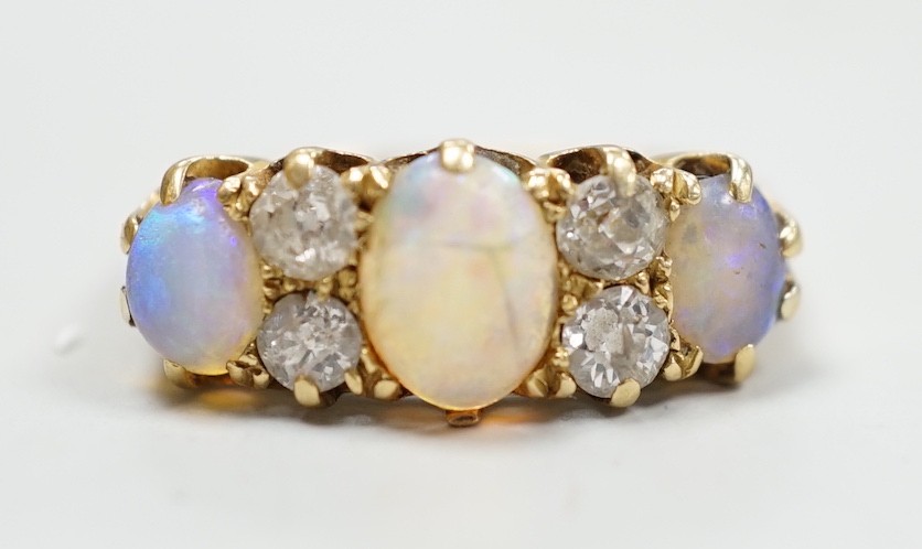 A late Victorian 18ct gold, three stone white opal and four stone diamond set half hoop ring, size M, gross weight 4.2 grams.